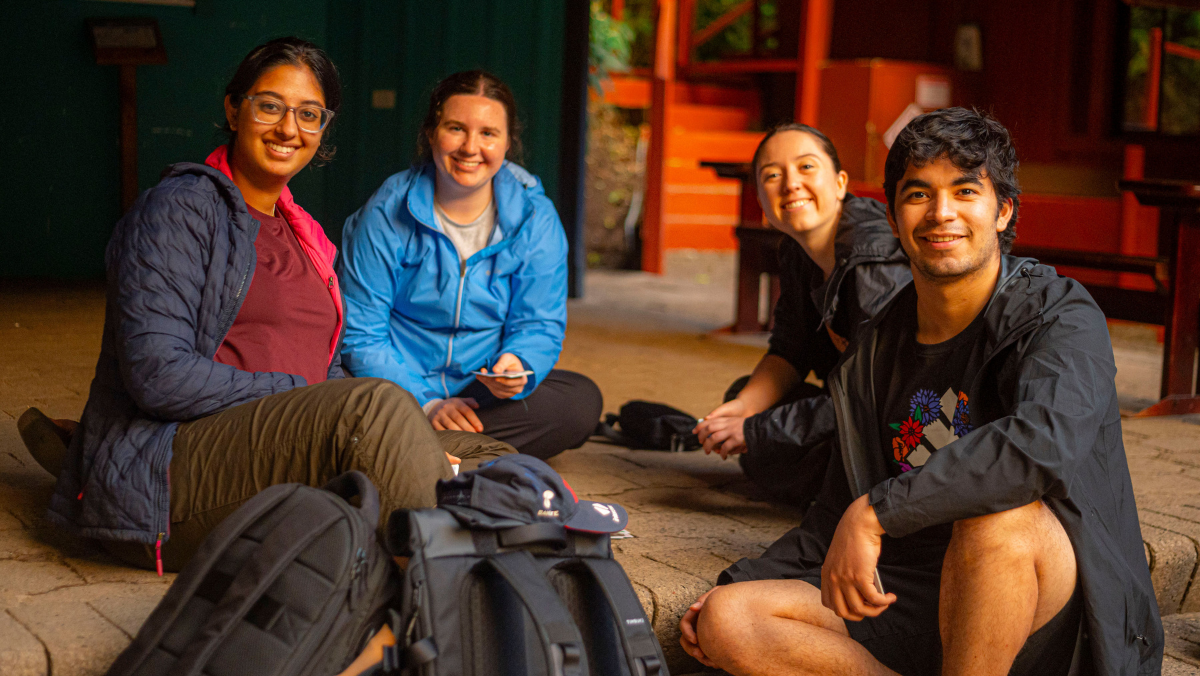 Students smiling while sitting on ground