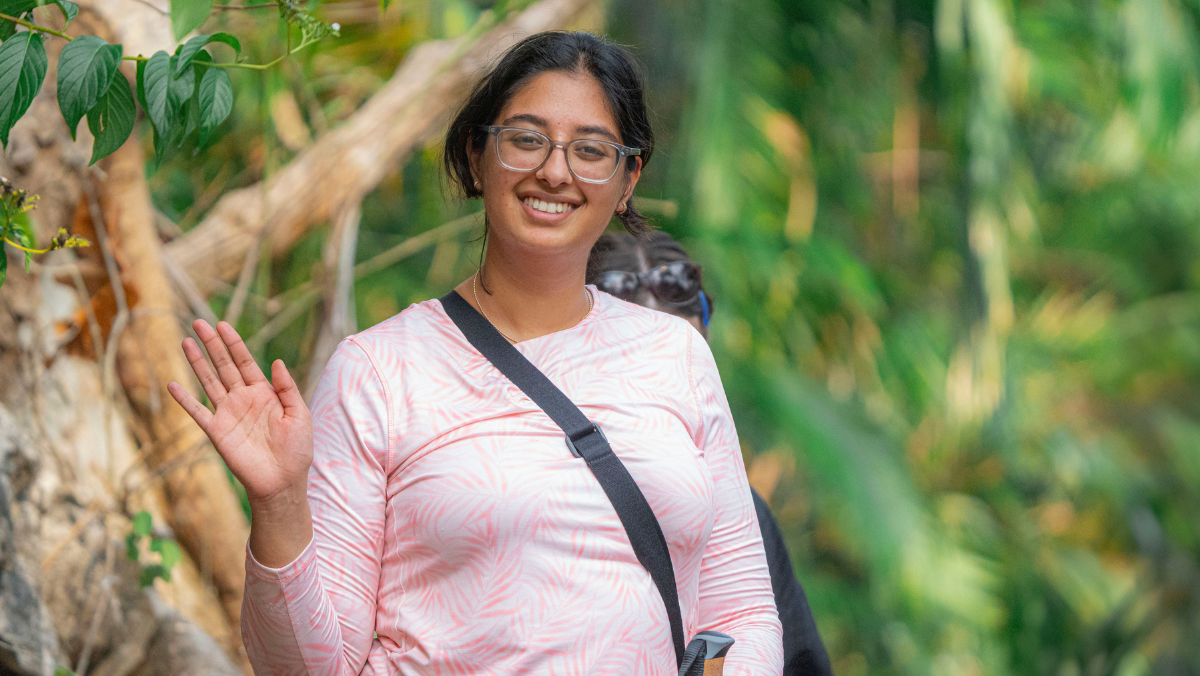 Student waving in forest