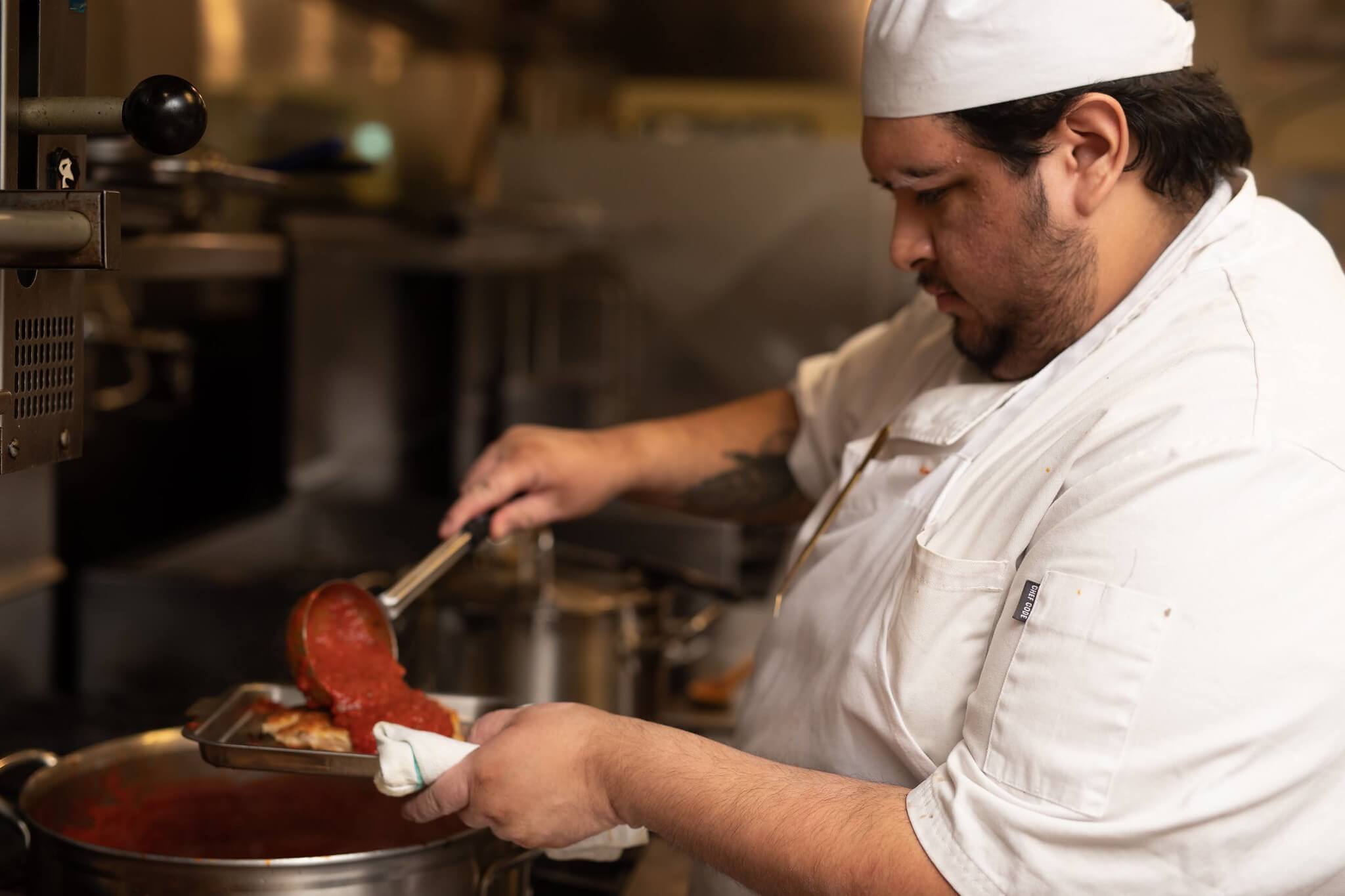 Hospitality Management student ladling sauce