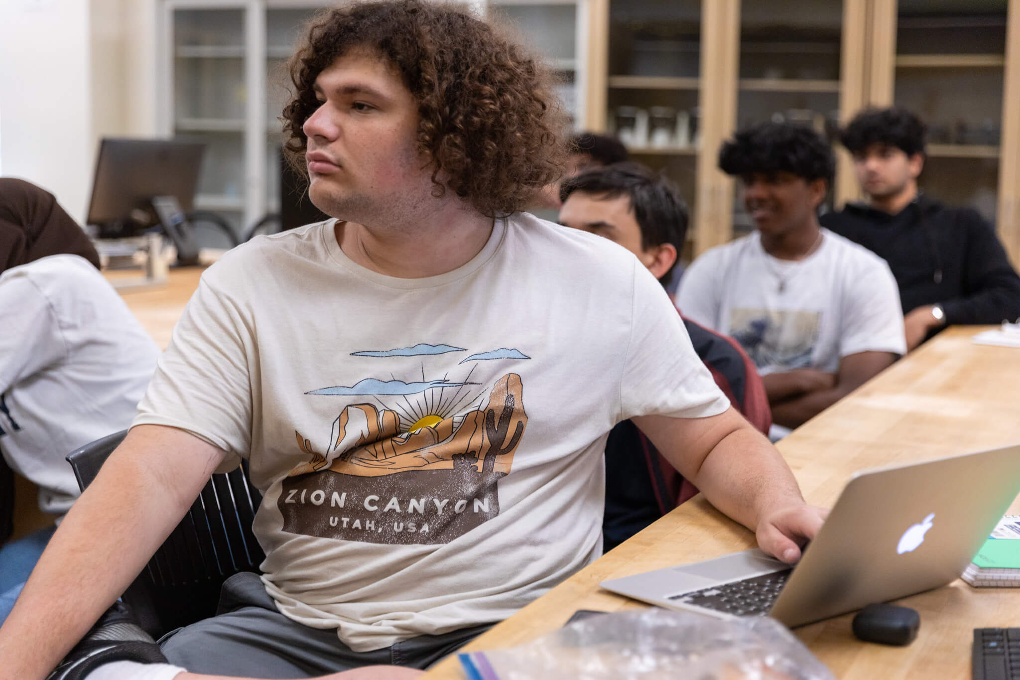 Mission College student in class on his laptop looking towards a speaker