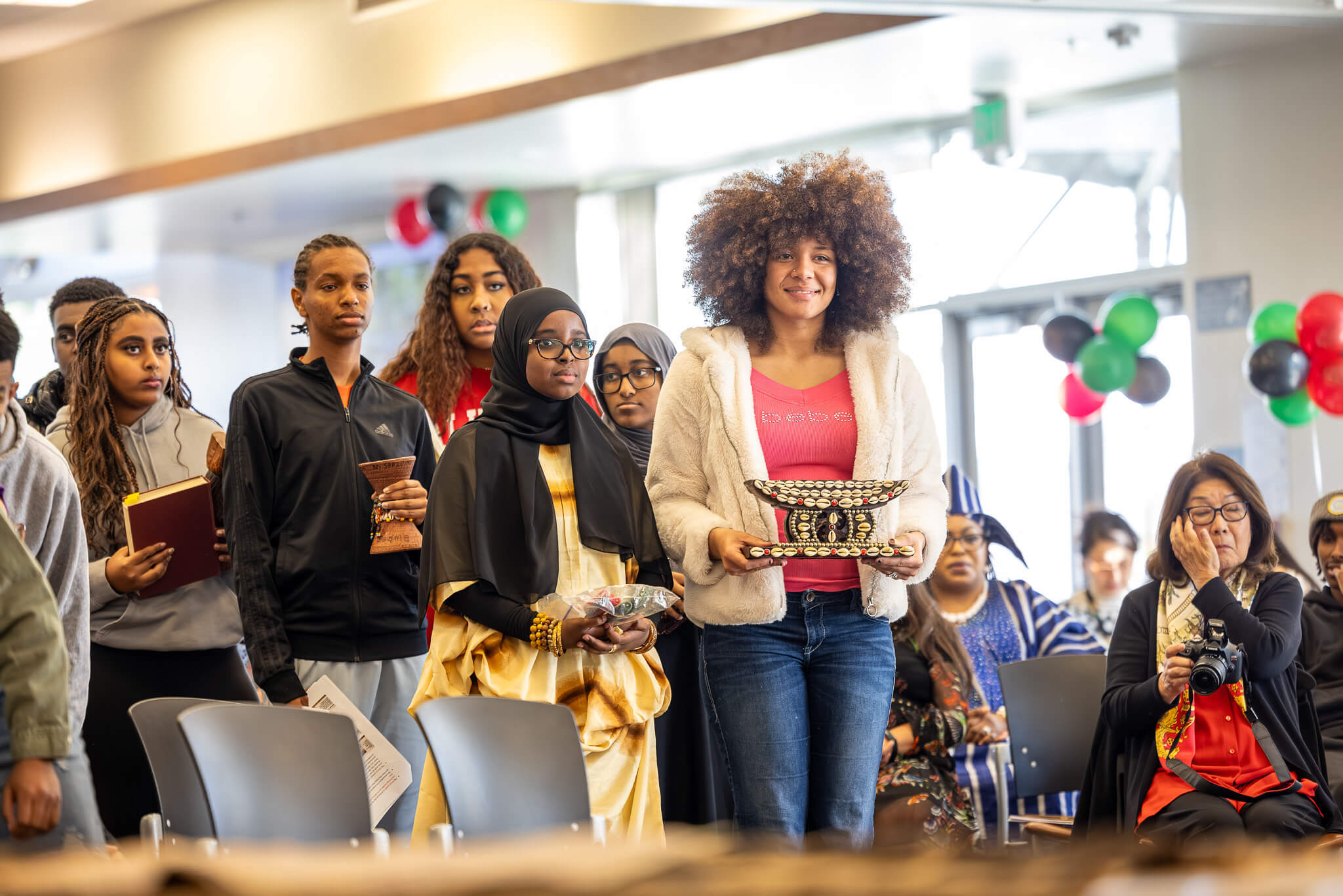 People carrying items up to the front of a room
