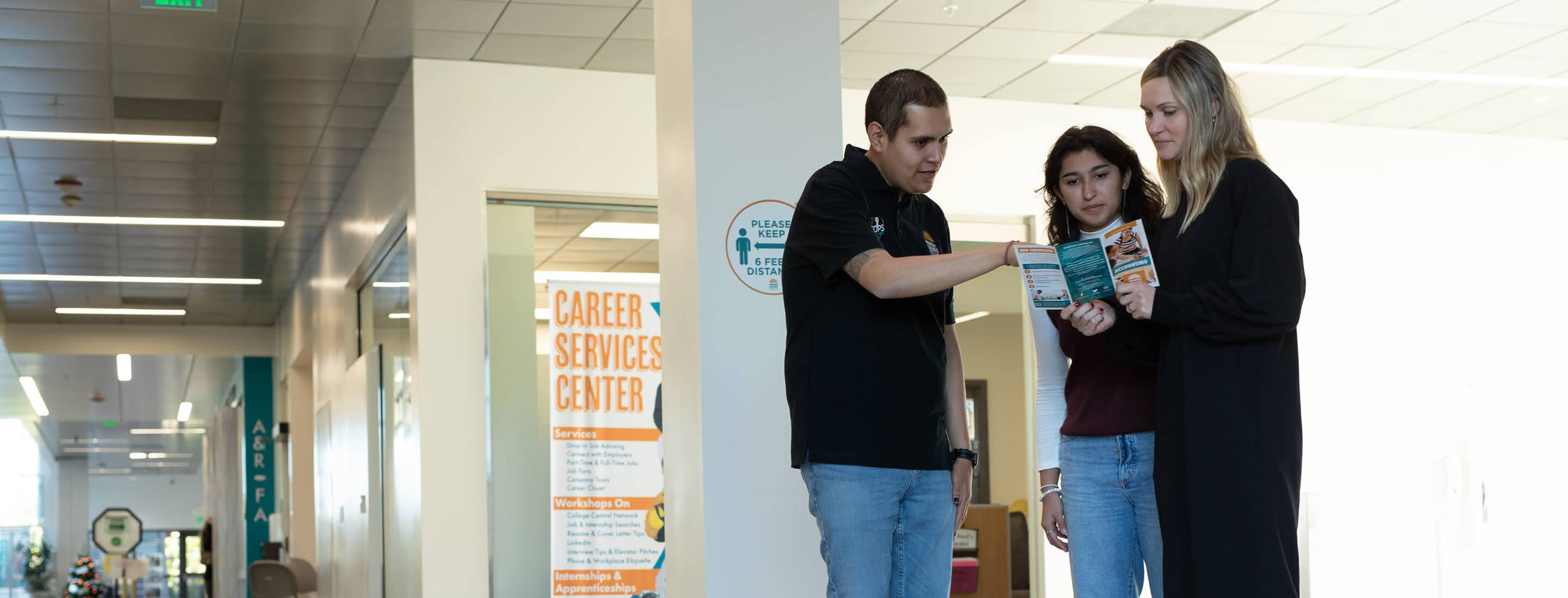 Three students talking and looking at a brochure