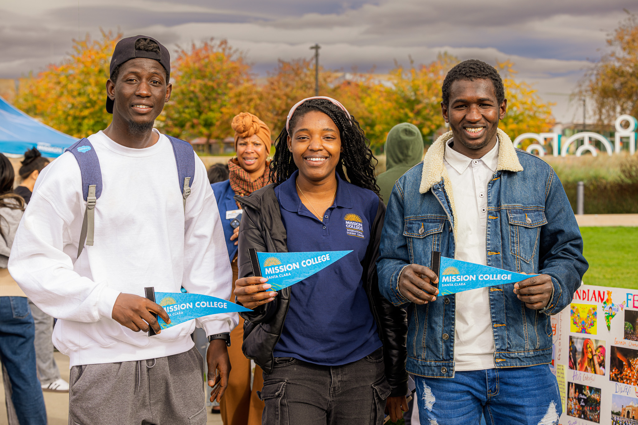 Three students holding Mission College banners