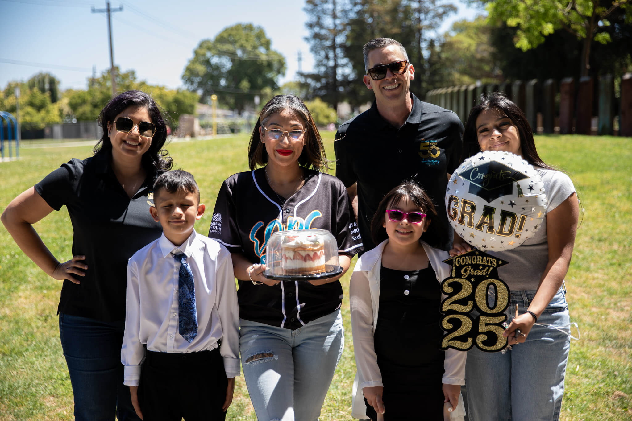 President Seher posing people includinga  graduate holding cake