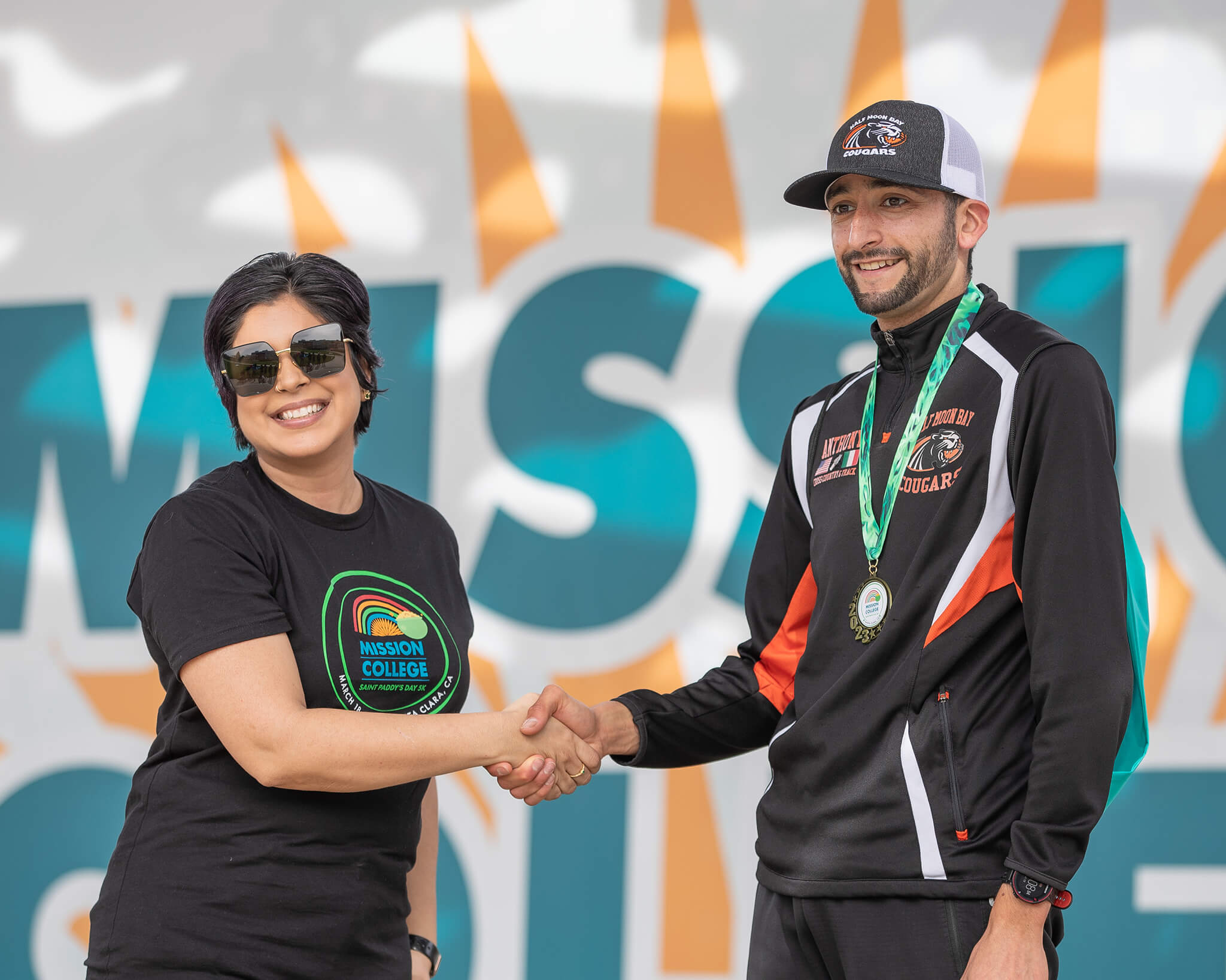 Seher Awan shaking the hand of a male student who won a medal