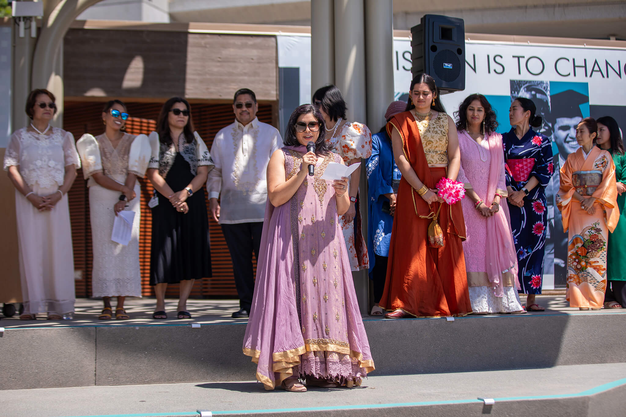 Seher Awan speaking at an event outside with people standing behind her