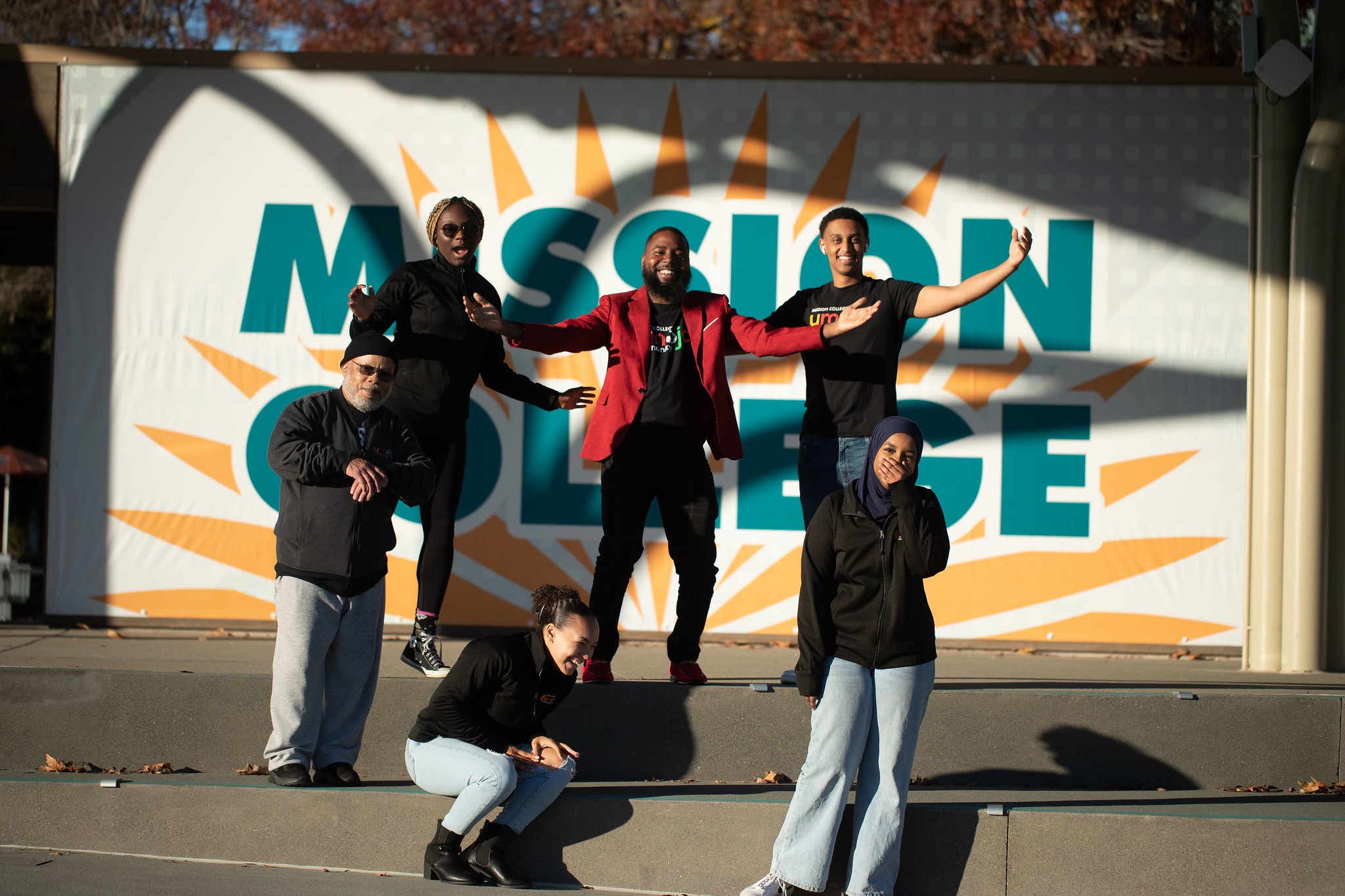 Students gathered laughing in front of Mission College sign