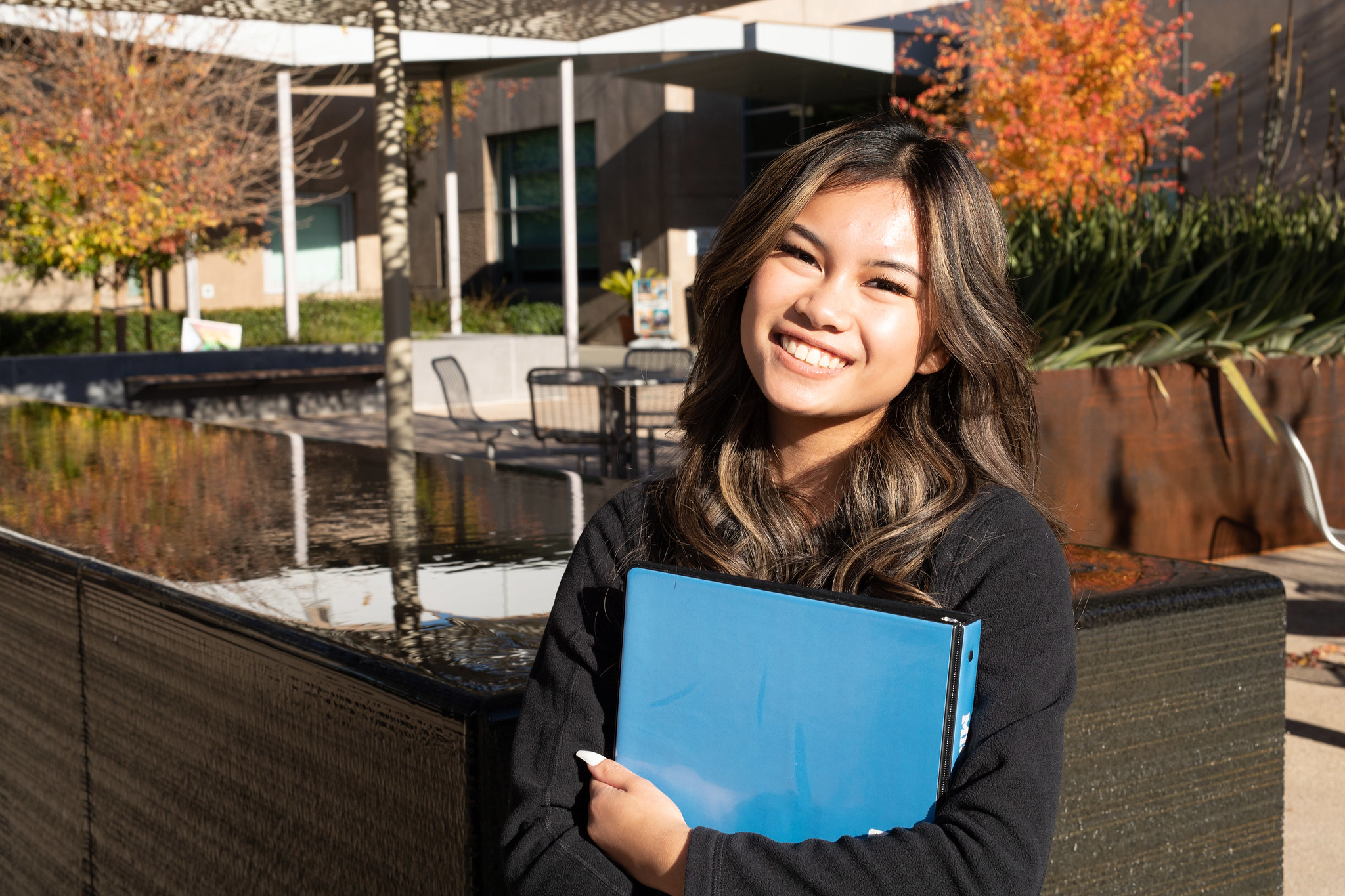 Mission College student smiling holding a blue binder